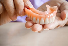 A closeup of hands holding a removable denture