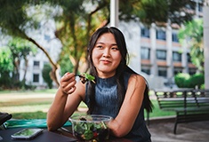 Woman smiling while eating healthy meals outside