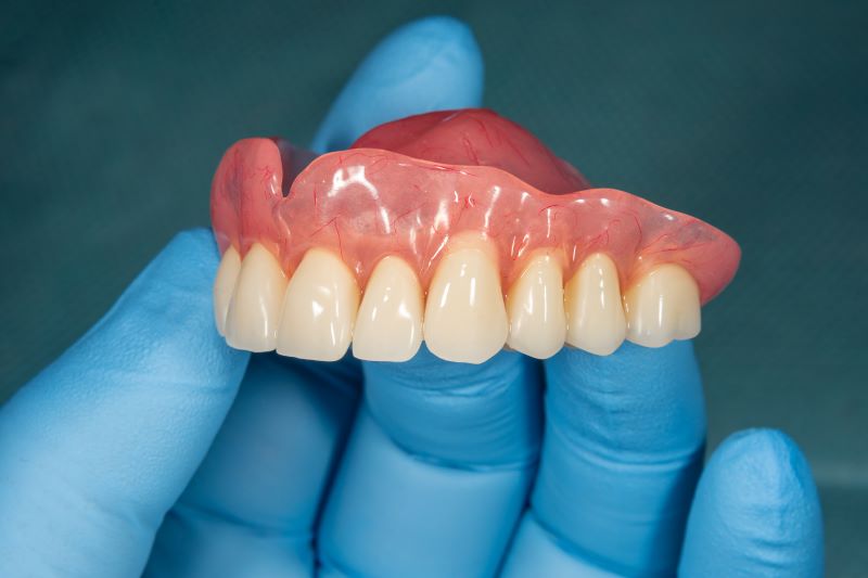 A dentist’s hand holding a denture